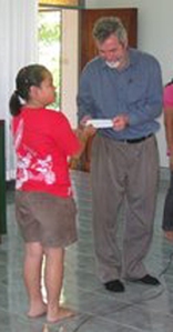 Dr. Neitzel receives a Haiti relief donation from children in Thailand church. 